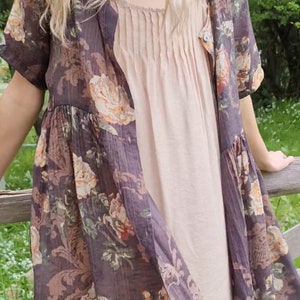 Puede incluir: Un vestido de estampado floral marr&oacute;n con un slip beige debajo. El vestido tiene un borde de encaje y mangas cortas.