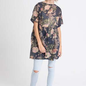 Puede incluir: Un vestido de estampado floral azul marino con mangas cortas y cintura fruncida. El vestido se lleva con jeans azul claro.