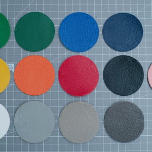 May include: Twelve round leather samples in various colours, including yellow, orange, red, green, blue, pink, grey, and white.