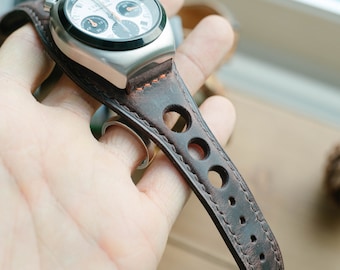 May include: A brown leather watch strap with stitching and holes. The strap is attached to a silver watch with a white face and black chronograph dials.