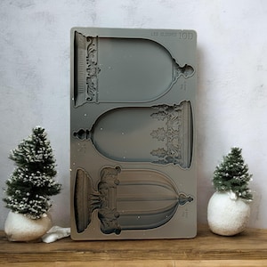 May include: A gray silicone mold with three different sized dome shapes. The mold is for making decorative items and has the text "LES CLOCHES IOD" on it.