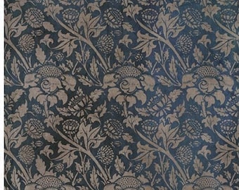 May include: A dark blue fabric with a repeating pattern of beige stylized flowers and leaves. The fabric has a vintage, distressed look. The text "Inspiraciones de William Morris" is at the top of the fabric.