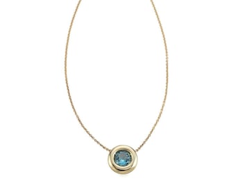 Op de afbeelding: Een gouden ketting met een ronde hanger met een blauwe edelsteen.