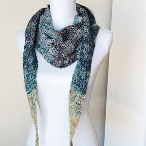 May include: A triangular scarf with a gradient of blue, green, and yellow colors. The scarf has a textured knit pattern and long tassels.