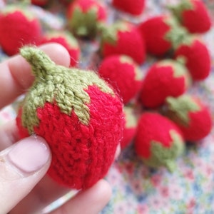 May include: A collection of knitted strawberries in red and green. The strawberries are made of yarn and have a realistic appearance.