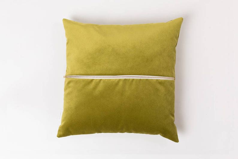 May include: A green velvet pillow with a zipper closure. The pillow is a solid color and has a subtle sheen.