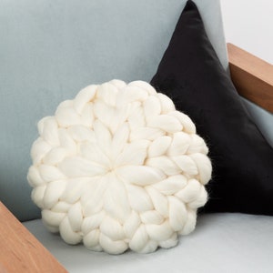 May include: A white chunky knit throw pillow on a light blue armchair with a black pillow behind it.