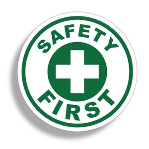 May include: A green and white round sticker with the text "SAFETY FIRST" in a circle around a white plus sign.