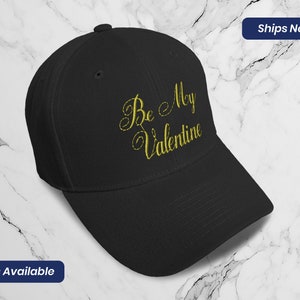 May include: Black baseball cap with gold embroidery that reads "Be My Valentine".