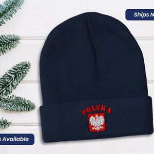May include: A navy blue knit beanie with the word "POLSKA" embroidered in red and a white and red eagle crest.