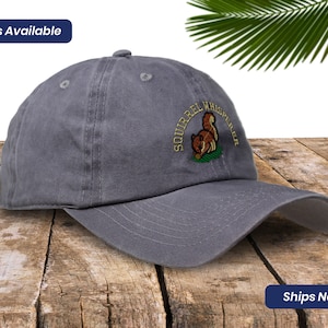 May include: Gray cotton baseball cap with an embroidered squirrel design and the text "Squirrel Whisperer".