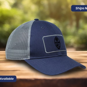 May include: A navy blue and gray mesh trucker hat with a black and white patch featuring the flag of Guam.