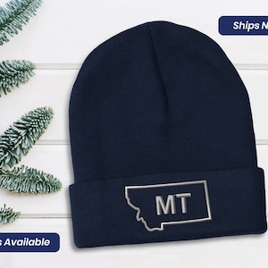 May include: A navy blue knit beanie with a gray outline of the state of Montana and the letters "MT" embroidered on it.