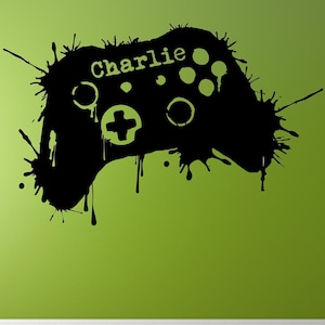 Op de afbeelding: Zwarte en witte silhouet van een videogamecontroller met verfspatten. De controller heeft de naam "Charlie" erop geschreven.