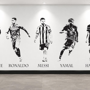 以下が含まれることがあります： 5人のサッカー選手のアクションポーズを描いた白黒のウォールステッカー。各選手のイラストの下には、MBAPPE、RONALDO、MESSI、YAMAL、HAALANDという名前がセリフ体フォントで印刷されています。