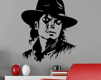 May include: A black vinyl wall decal featuring a stylized portrait of a person wearing a fedora hat. The graphic design uses high-contrast black lines to define the facial features, hair, and hat, creating a bold silhouette against the wall surface.