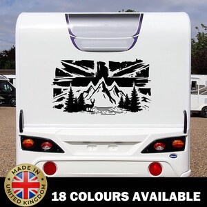 May include: A white caravan with a black graphic featuring mountains, trees, and a deer, set against a Union Jack. The text "18 COLOURS AVAILABLE" is displayed below. A "Made in United Kingdom" sticker is also visible.