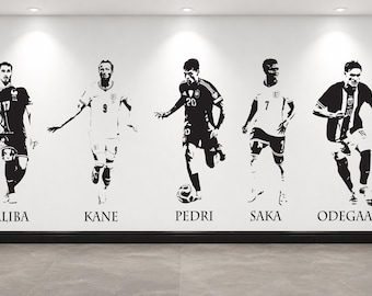 Puede incluir: Un vinilo decorativo en blanco y negro que muestra a cinco jugadores de fútbol en poses de acción. Los nombres Saliba, Kane, Pedri, Saka y Odegaard están impresos en una fuente serif debajo de cada figura individual en la pared.