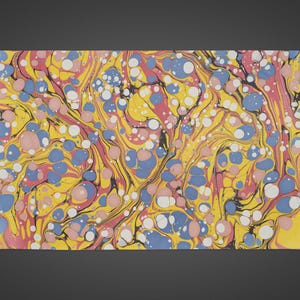 May include: A rectangular sheet with a vibrant, marbled pattern. The design features a yellow base with swirling pink, blue, and black lines. White and blue circles are scattered throughout the design, creating a dynamic and colourful composition.
