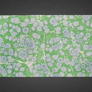 May include: A rectangular sheet with a marbled design. The pattern features green and grey circular shapes, connected by thin white lines, creating a unique texture. The paper has a smooth finish, reminiscent of traditional bookbinding.