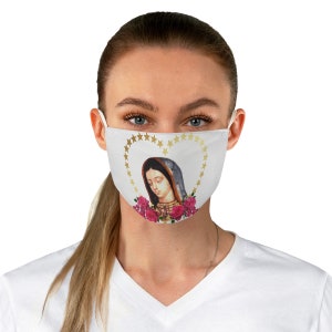 May include: A white face mask with a gold heart-shaped design featuring a depiction of the Virgin Mary with pink roses. The design includes a gold halo and a gold star border.