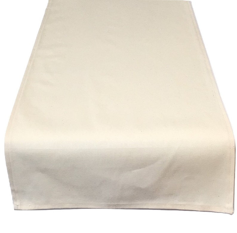 May include: A plain white cotton table runner. The runner is rectangular and has a simple, unadorned design.