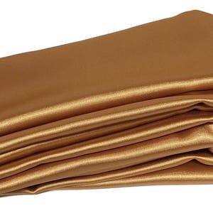 May include: A folded piece of gold satin fabric. The fabric is smooth and shiny.