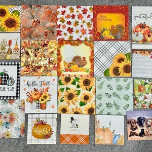 May include: A collection of twenty square paper napkins featuring various autumn-themed designs, including sunflowers, pumpkins, turkeys, fall foliage, plaid patterns, and illustrations of Snoopy, owls, and dogs with text like Happy Fall Y'all and grateful.
