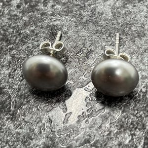 May include: A pair of silver stud earrings with dark grey pearl accents.