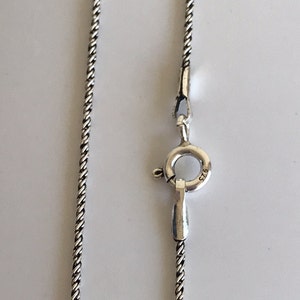 May include: A silver chain necklace with a lobster clasp. The clasp is marked with "925", indicating that the necklace is made of sterling silver.