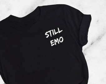 May include: Black t-shirt with the text "STILL EMO" printed on the front in white.