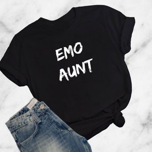 Pode incluir: Camiseta preta com texto branco que diz "EMO AUNT" em uma fonte desgastada.