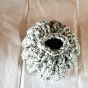 May include: A gray crocheted basket with a round opening. The basket is made of a soft, textured yarn.