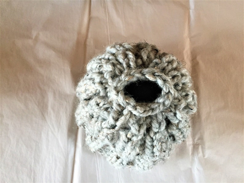 May include: A gray crocheted basket with a round opening. The basket is made of a soft, textured yarn.
