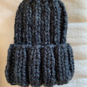 May include: A dark gray knitted beanie hat with a ribbed texture.