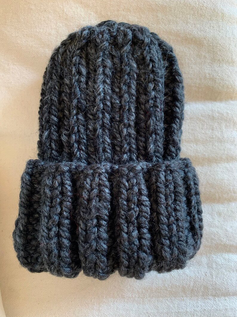 May include: A dark gray knitted beanie hat with a ribbed texture.