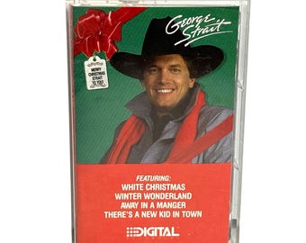 May include: A cassette tape case with a green background and a red bow. The case features a photo of George Strait wearing a cowboy hat and a red scarf. The text on the case reads "Merry Christmas Strait to You" and "Featuring: White Christmas, Winter Wonderland, Away in a Manger, There's a New Kid in Town". The case also includes the text "Digital".
