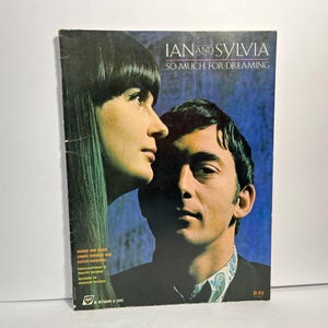 Può includere: Copertina di un libro di musica vintage con Ian e Sylvia, intitolato "So Much for Dreaming". La copertina ha uno sfondo blu con una foto di un uomo e una donna. Il testo include "Parole e musica, simboli di accordi e diagrammi di chitarra."