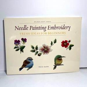 May include: A book titled "Needle Painting Embroidery" with the subtitle "Fresh Ideas for Beginners." The cover features embroidered floral and bird designs in various colors, including purple, red, and blue. The author's name, Trish Burr, is also visible.