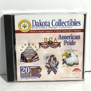 May include: A CD-ROM case featuring the "Dakota Collectibles Embroidery Design Collection." The cover displays patriotic designs, including the U.S. Capitol, an eagle, and the words "American Pride" and "USA." The case contains 20 designs.