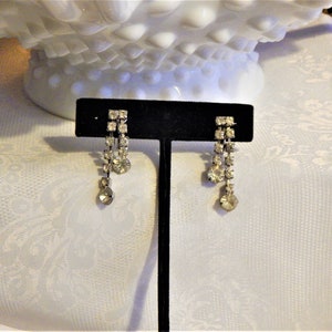 May include: A set of three ceramic mugs with a speckled, cream-colored glaze. Each mug features a different hand-painted design: a blue and green leaf, a yellow flower, and a red berry. The mugs have a simple, modern design.