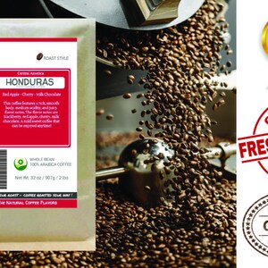 May include: A brown paper bag with a white label featuring the text "Smokin Beans" and "Honduras". The label also includes a description of the coffee's flavor profile, which includes notes of red apple, cherry, and milk chocolate. The bag is sitting on a pile of roasted coffee beans.