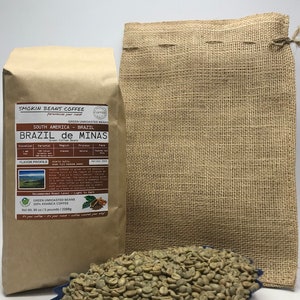 May include: A brown paper bag with a label that reads "Smokin Beans Coffee" and "Brazil de Minas Green Coffee Beans". The bag is sitting on a burlap sack. A blue tray holds a pile of green coffee beans.