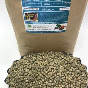 May include: A brown paper bag with a label that reads "Tanzania Peaberry Green Coffee Beans". The label includes information about the coffee's origin, variety, processing method, and flavor profile. The bag contains green coffee beans.