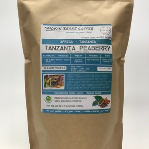 May include: A brown paper bag with a label that reads "Smokin Beans Coffee" and "Tanzania Peaberry Green Coffee Beans". The label also includes information about the coffee's origin, variety, region, process, farm, flavor profile, and recommended roast level. The bag contains 32 ounces of green unroasted coffee beans.