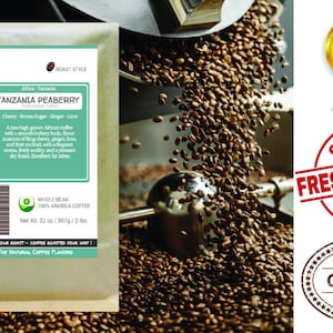 May include: A bag of Tanzanian Peaberry coffee beans with a brown sugar, ginger, and lime flavor profile. The bag is labeled with the text "Smokin Beans" and "100% Arabica Coffee".