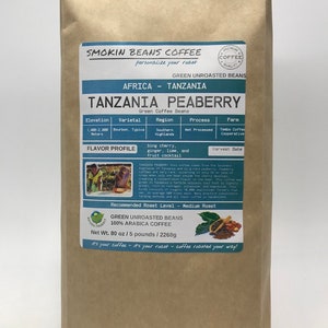 May include: A brown paper bag with a label for Tanzania Peaberry green unroasted coffee beans. The label includes details about the coffee's origin, varietal, region, process, farm, flavor profile, and recommended roast level. The bag is 80 ounces or 5 pounds (2268 grams).