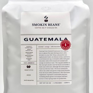 May include: A white stand-up pouch of Smokin Beans Guatemala coffee. The label features the text SMOKIN BEANS, COFFEE AS IT SHOULD BE, GUATEMALA, SINGLE ORIGIN, 100% ARABICA, and NET WT 80 OZ | 5 POUNDS | 2268 G, along with flavor notes and roast details.