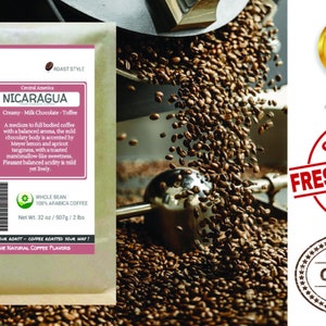 May include: A brown paper bag with a white label that reads "Smokin Beans Coffee" and "Nicaragua". The label also includes information about the coffee's origin, flavor profile, and roast style. The bag is sitting on a table with a pile of roasted coffee beans in the background.