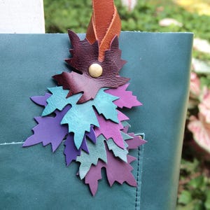 Bonito bolso de otoño hecho a mano con borlas y hojas caídas de color morado.